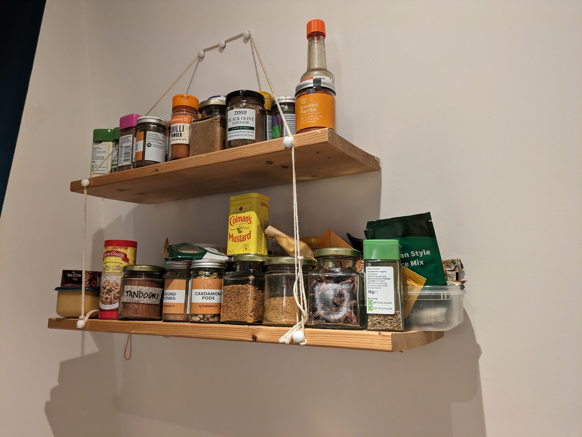 A spice shelf in a kitchen utilising hinges on a slanted wall